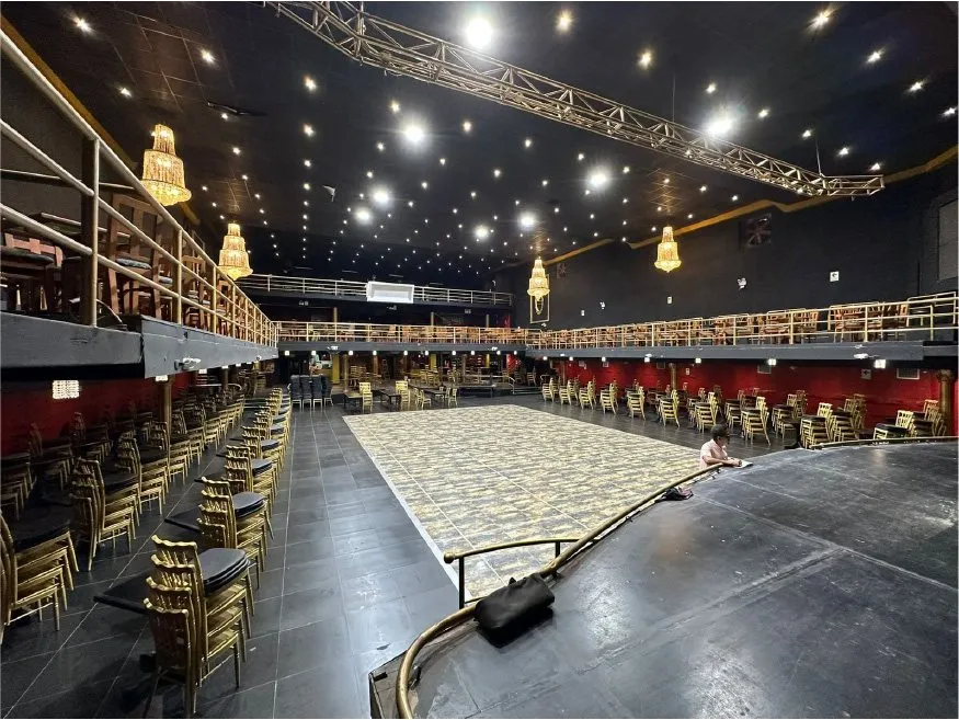 Salón principal vacío con pista central, mezanine perimetral y estructura de truss