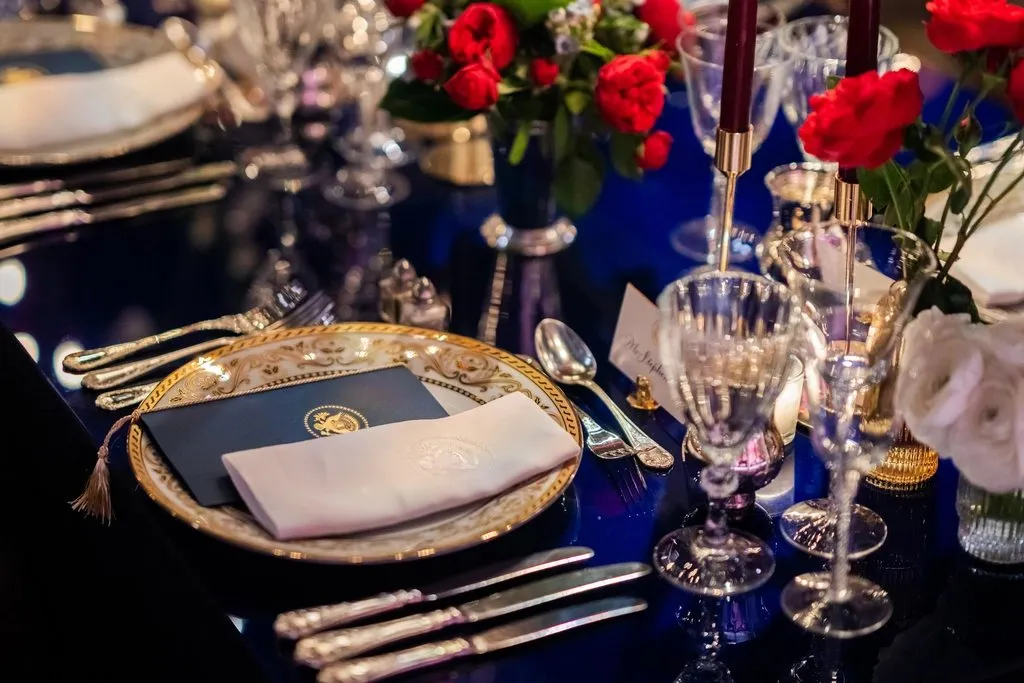 Mesa de gala montada con vajilla dorada y arreglos florales